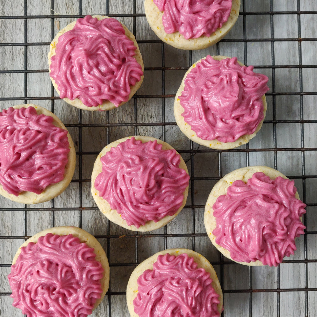 Vegan Gluten-free sugar cookies with raspberry frosting on a cooling rack